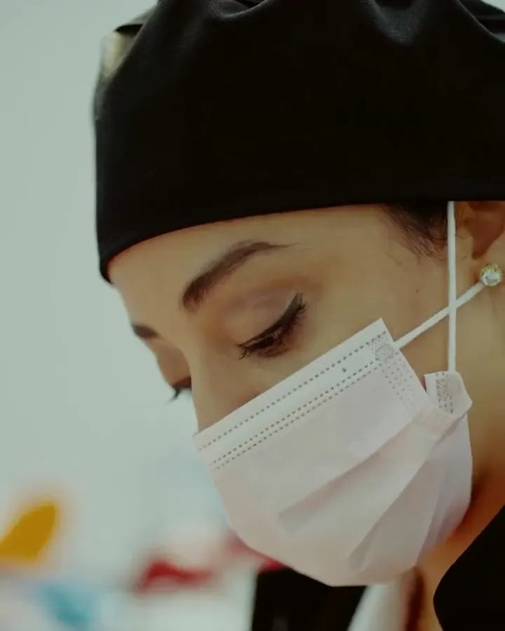 La Dra. Kim Rubattino con gorro negro y mascarilla, concentrada en su trabajo en la clínica.